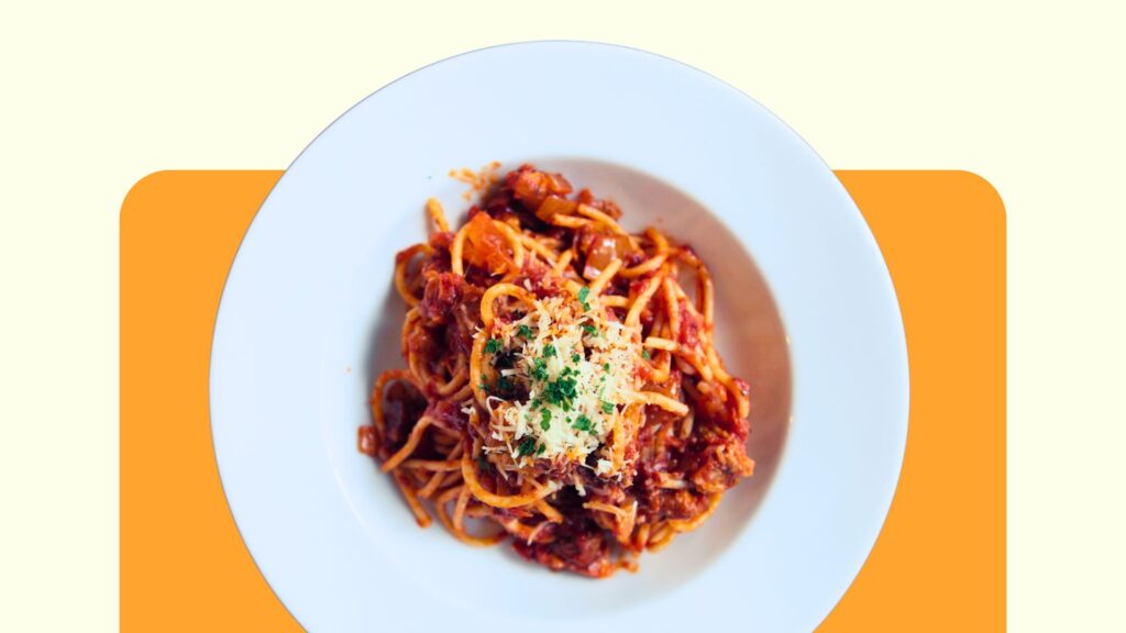 a bowl of spaghetti bolognese appears on an orange background